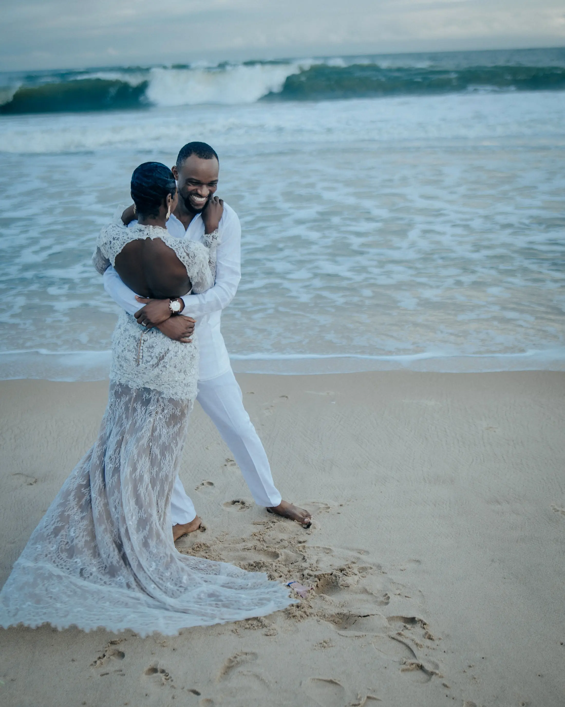 A couple embracing on the sand at the water's edge