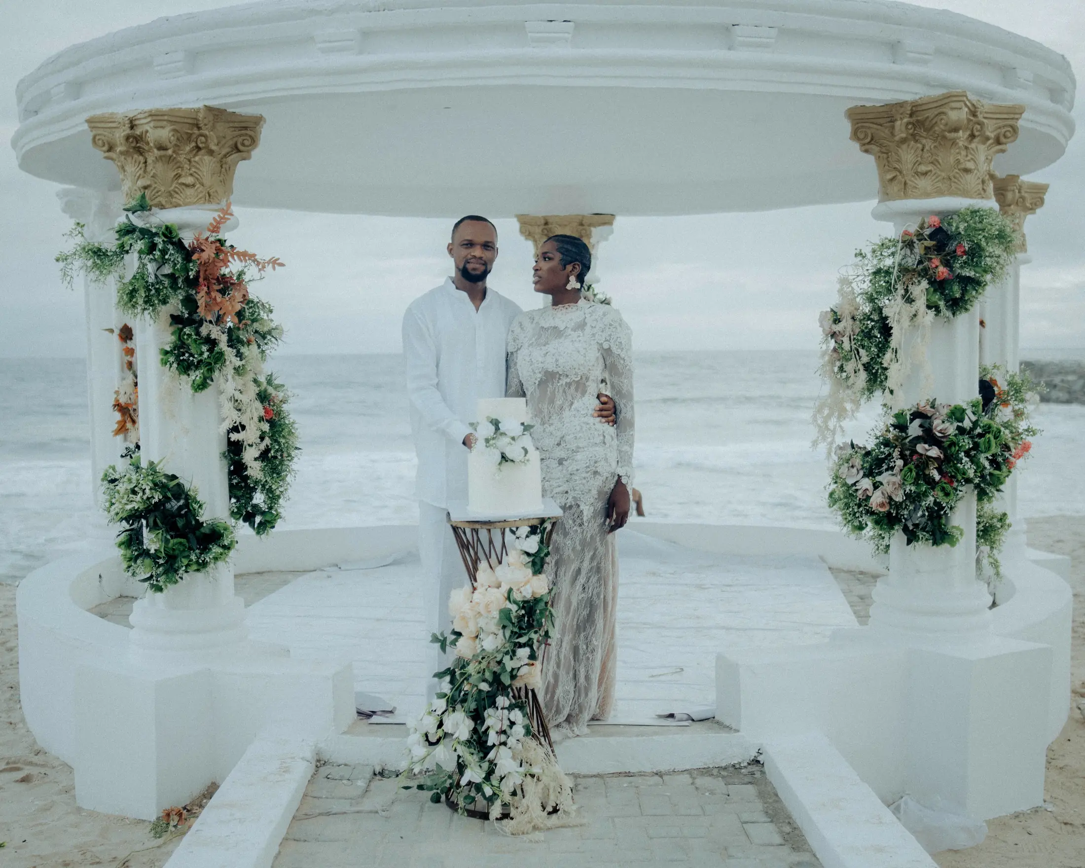 Bride and groom at the gazebo, white flowers wound round the columns