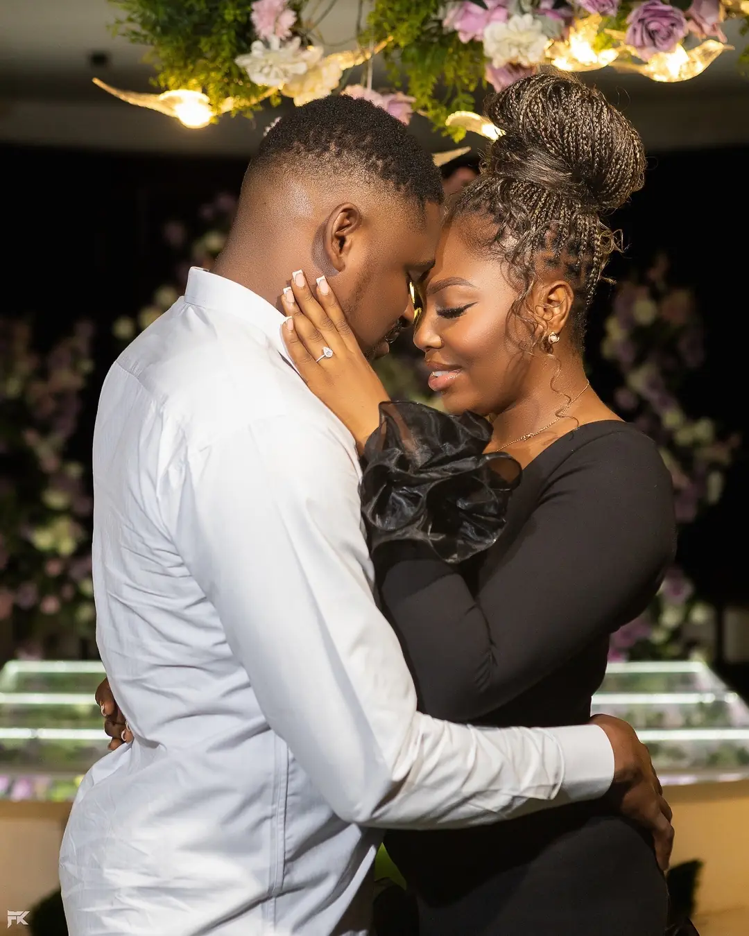 A newly engaged couple embracing under flowers