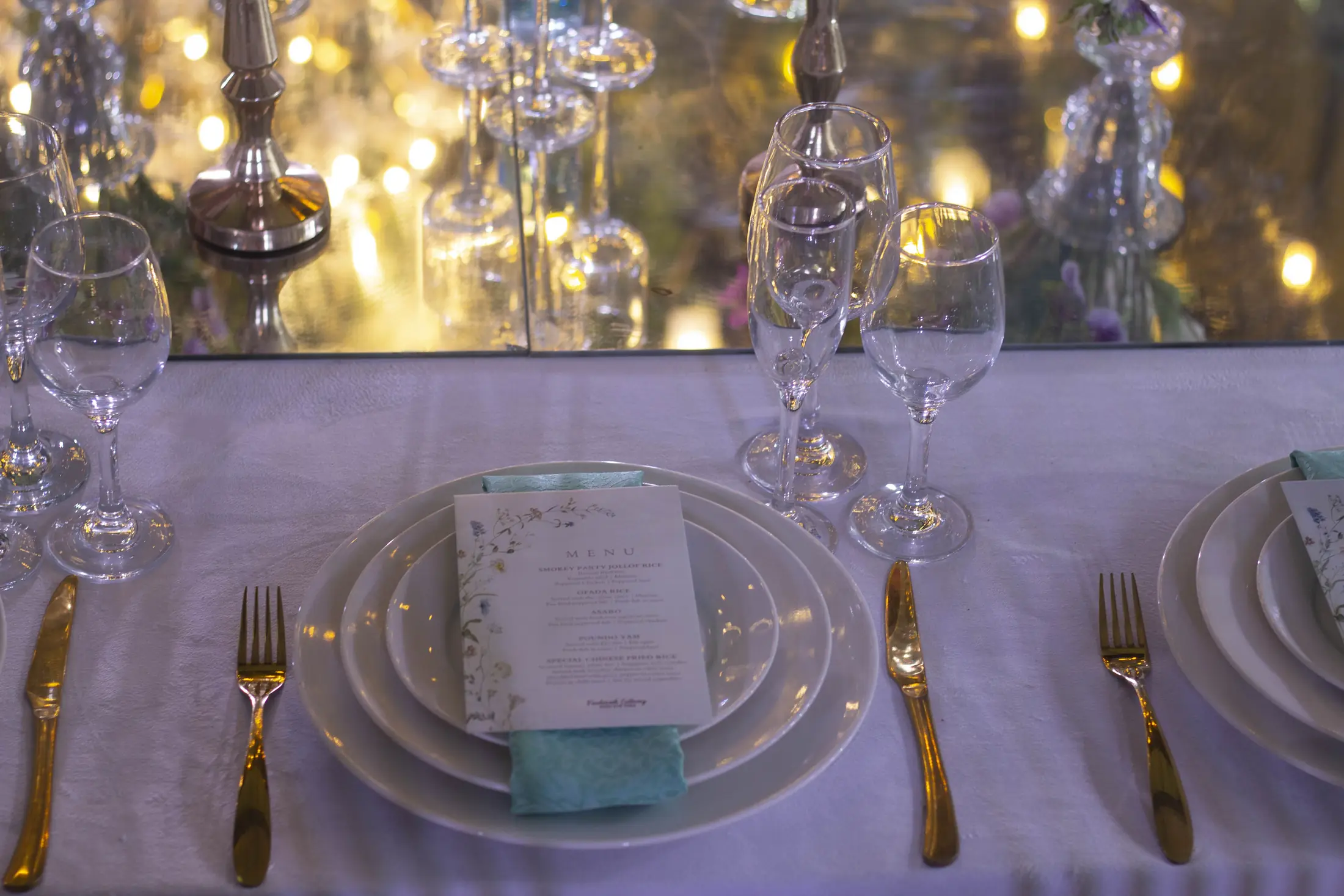 Gold-rimmed plates and glassware at a wedding table